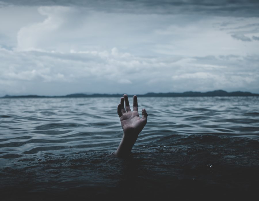 hand reaching above the water line of body of water